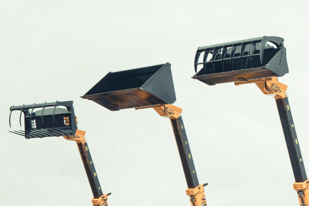 Comparaison de trois types de godets de chargeuse : godet grappin, godet standard et godet grand volume pour chantiers BTP