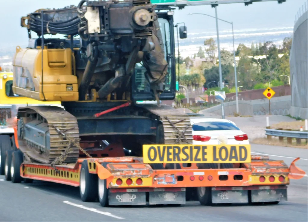 Excavatrice chargée sur une remorque pour transport sécurisé.